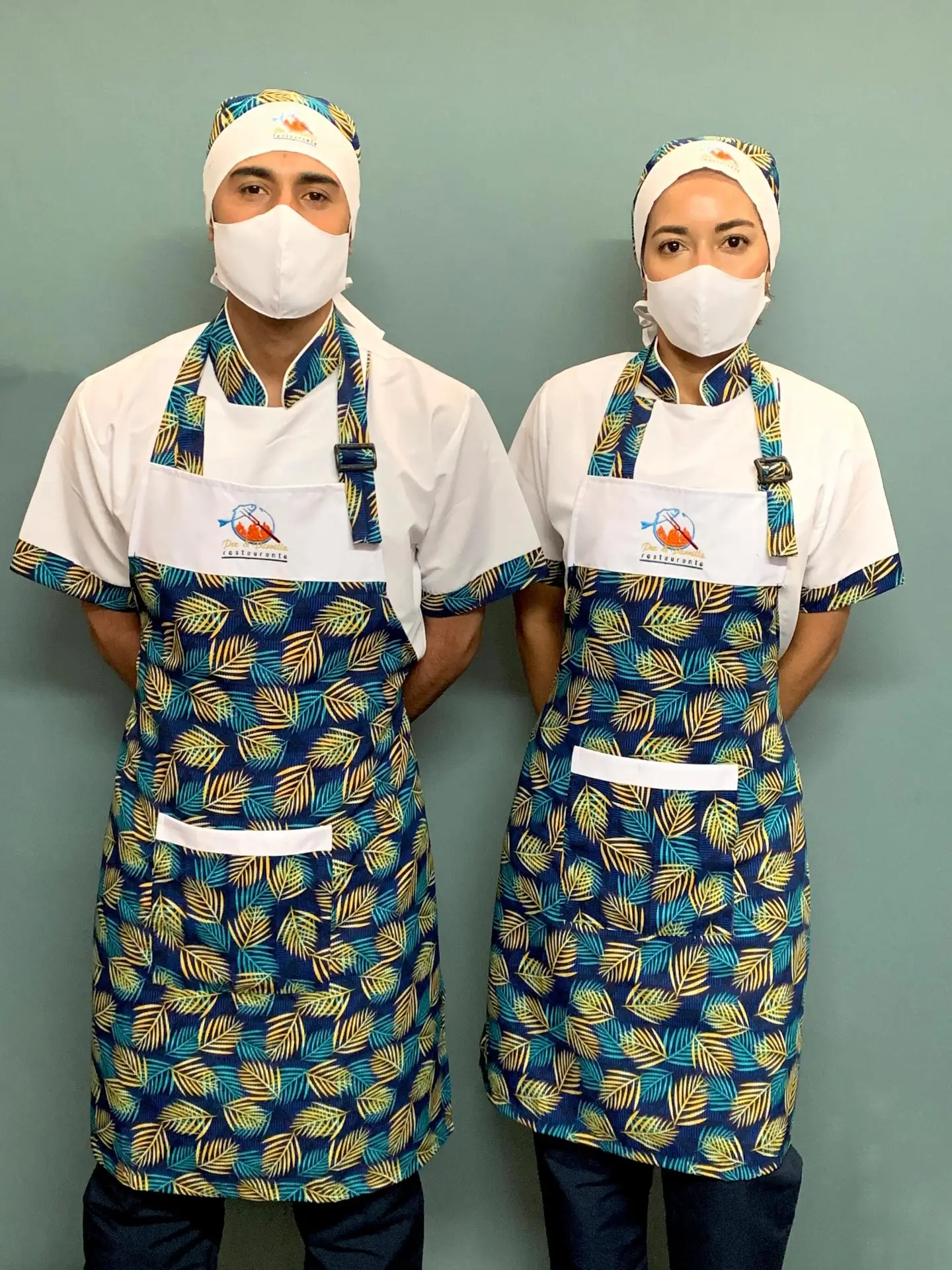 Equipo de restaurante con camisas blancas, delantales estampados y cofias