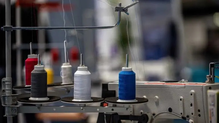 Carretes de hilo de colores en una máquina de confección de uniformes